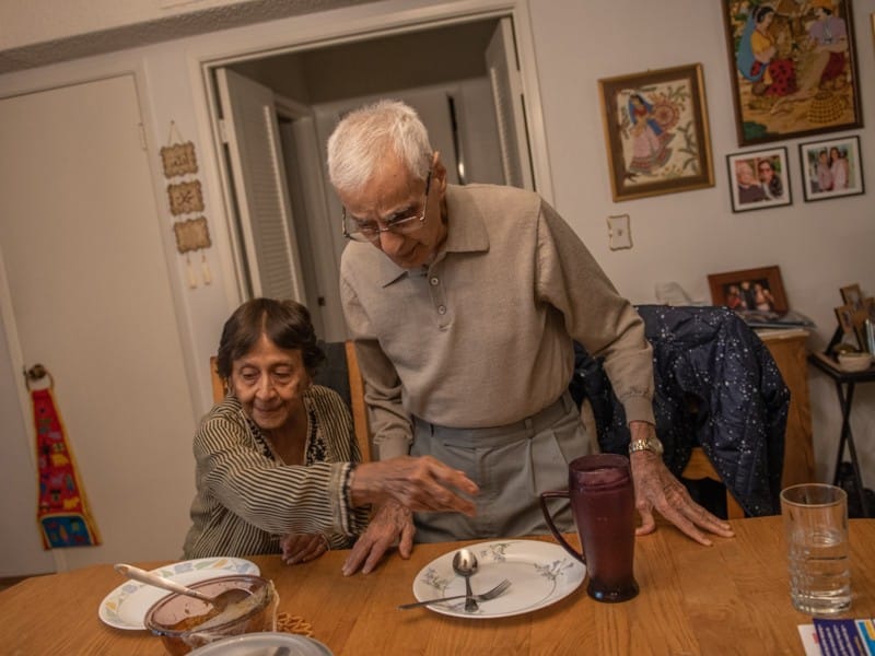 Tahera Khalil helps her husband Sabbar Kahlil at dinnertime. Photo by Sree Sripathy for India Currents/CatchLight Local