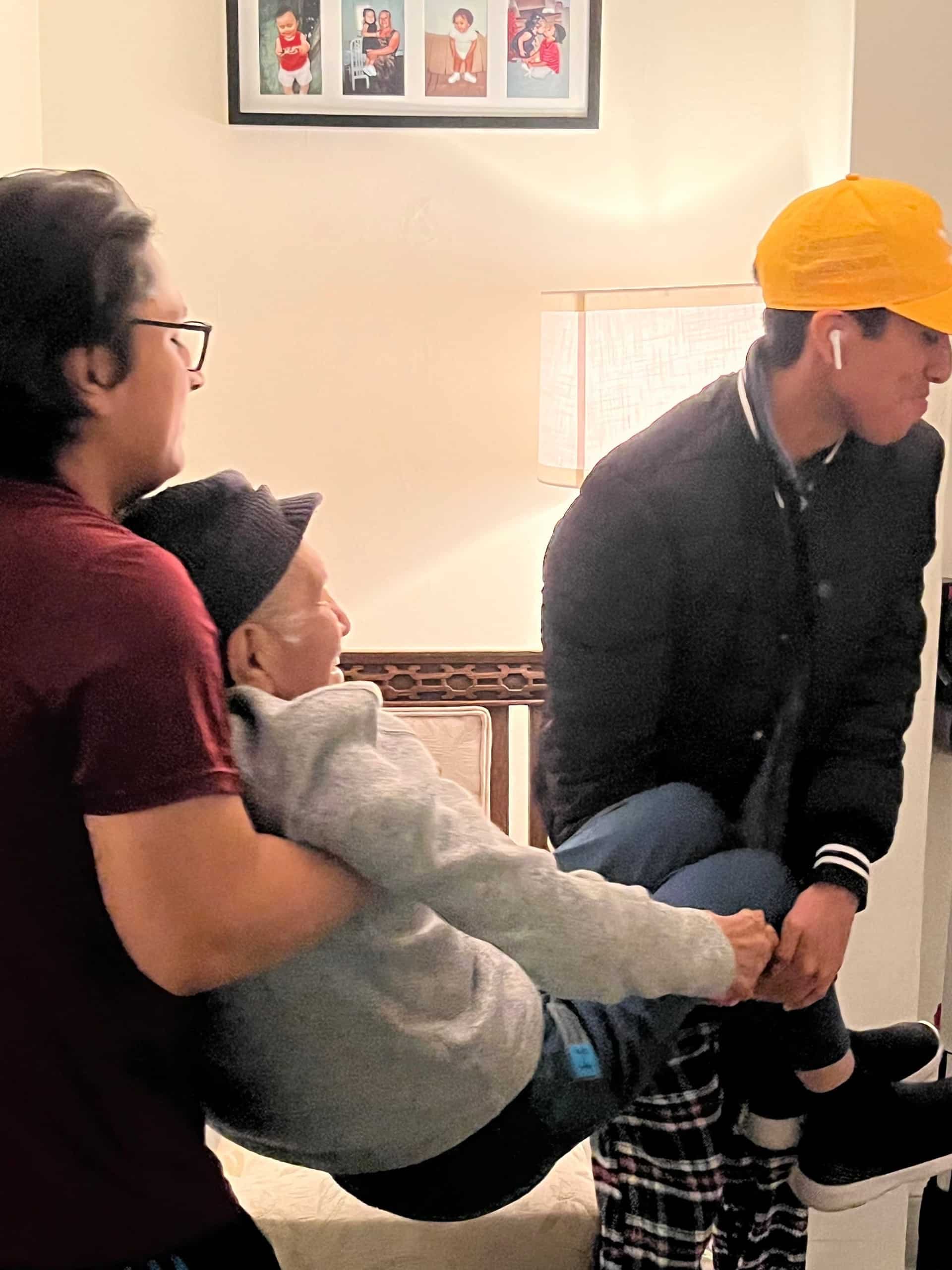 Doroteo López is carried to the bathroom by his grandsons Joshua and Jesse. Photo courtesy of Lilian Pérez